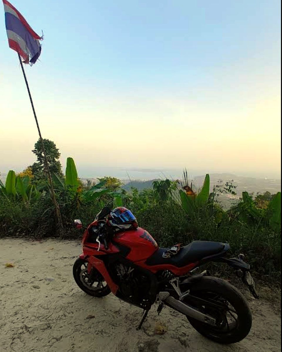 Red Honda next to a Thai flag on a hilltop